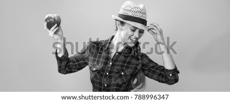 Healthy food to your table. Portrait of happy modern woman farmer in checkered shirt isolated on yellow background dancing with an apple