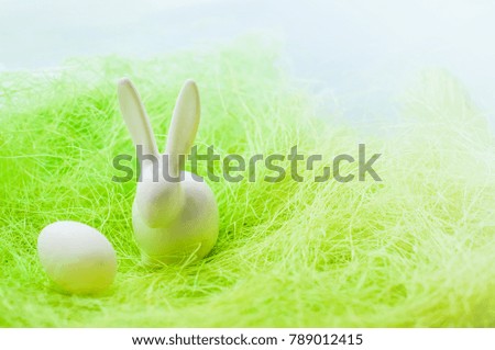Row of easter egg quail with white rabbit on the green dry grass hay.