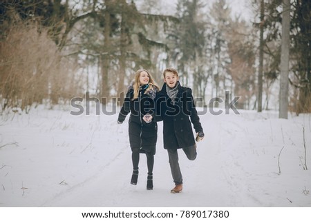 beautiful couple in love walking in the snowy winter woods