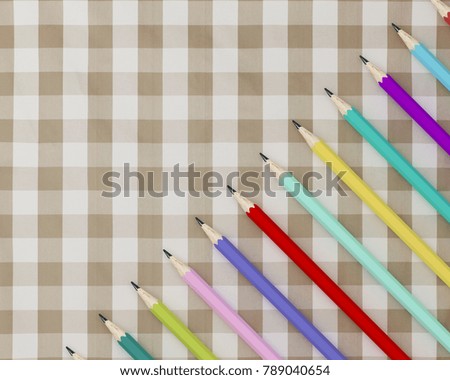 Creative flat lay design of crayons, Many colorful pencils on fabric tartan plaid pattern background. minimal idea concept.