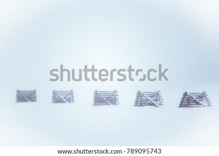 Beautiful snowy winter season landscape with grunge wooden barriers against windblown snow, barely visible in cold bright fog. Abstract  minimalist foggy white nature background wallpaper.