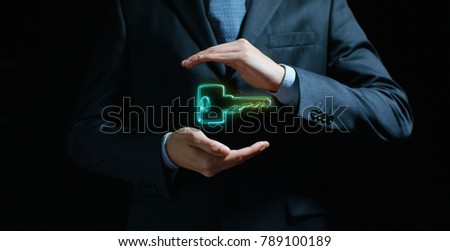 To a man in a suit and tie appears a futuristic graphic of the key in his hands. Concept of: security, secret codes, new house and future