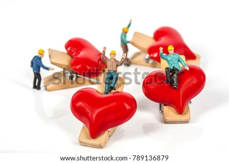 selective focus of miniature workers holding red heart shape wood clip isolated on white background , abstract background to valentine concept.