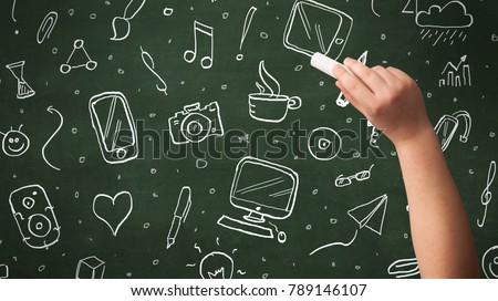 A person drawing media and communication icons on school blackboard with chalk