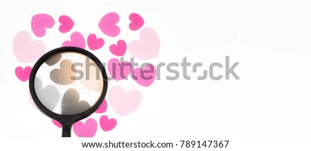 Soft focus of Magnifying glass with orange light and  multi pink heart shape white background, Love concept ,Background for Valentine with copy space