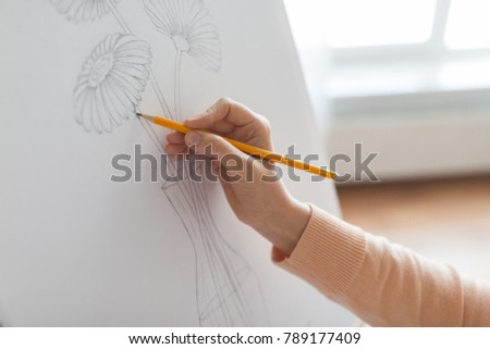 art, creativity and people concept - artist hands with graphite pencil drawing still life picture of flower in vase on paper at studio