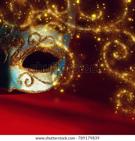Image of elegant blue and gold venetian mask over red background