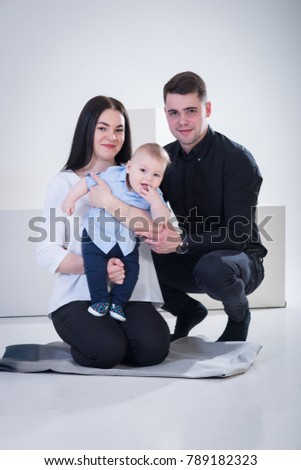 Young happy family with baby boy shooting in the photo studio, smiling, posing on white background
