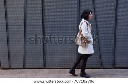 woman walking next to an iron texture wall