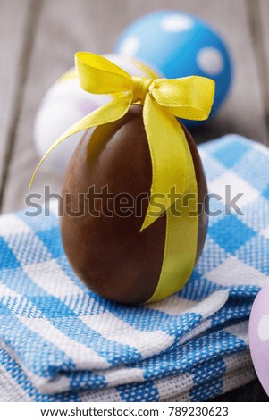 Easter egg made of chocolate, tied with a yellow ribbon, close-up