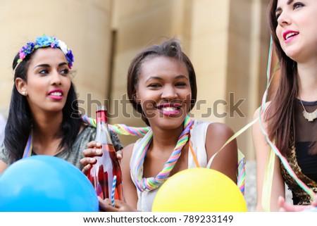 Four young women on hen night party drinking champagne on stairs