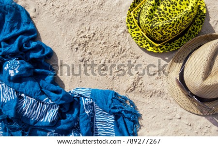 composition still life on the shore female and male hat yellow sunglasses blue pareo towels cape lying on the yellow sand summer day rest at the weekend