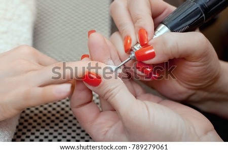 The master of the manicure saws and attaches a nail shape during the procedure of nail extensions with gel in the beauty salon. Professional care for hands.