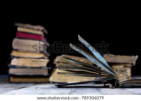 Old destroyed books on a wooden table. Reading room library with very old books on a wooden table. Black background.