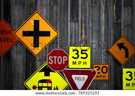 Collection of various road signs on rustic wooden wall 