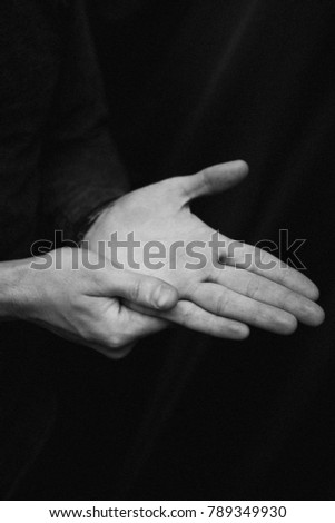 black and white photograph of man's hands on a black background