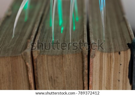 Macro photo of glowing glass fiber cables connected with old books.