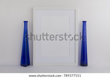A4 A3 A5 white wooden empty photo frame with empty space for your own overlay.  Perfect for blogger or website designer for light minimal feminine branding. Frame standing next to glass bottles. 