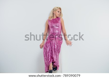 Happy young woman in an evening dress celebrating on a white background.