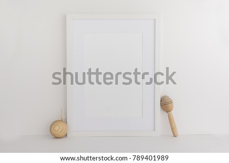 A4 A3 A5 upright white wooden photo frame standing next to wooden toys. Blank photo frame for text or work overlay perfect for blogger or website designer or marketing person. 