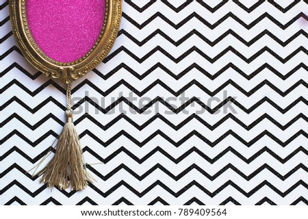 Vintage golden oval picture frame on black and white chevron background, with copy space in the frame 