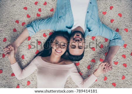 I love you. Top above view close up photo of excited cheerful joyful amazing beautiful man and woman, casual clothes, holding hands, cuddle, touching heads, surrounded by little red hearts