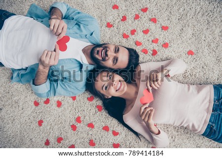 I'll give you my heart! Man decided to show his feelings!  Top view photo of excited cheerful lovely cute beautiful lovers holding heart cards in hands, lying on the floor