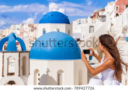 Travel tourist taking phone picture of Santorini Blue dome church, touristic attraction in Europe, European vacation banner. Woman taking smartphone photo of famous destination.