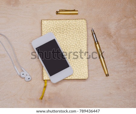 golden diary for notes with pen pen and white phone, macro photo from top on light background,flat lay photo