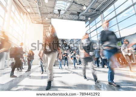 large crowd of anonymous blurred people rushing in a modern hall