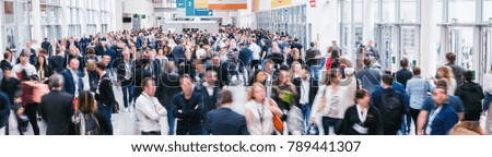 large crowd of anonymous blurred people at a trade show