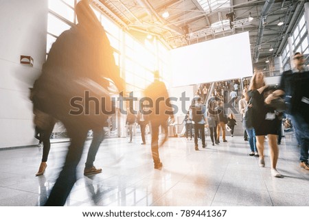 anonymous blurred people at a trade show, including copy space banner 