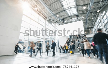 blurred people at a trade show, including copy space banner 