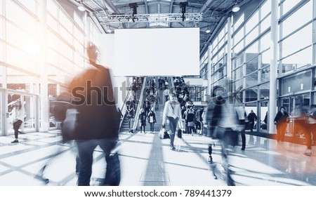 crowd of blurred people at a trade show, including copy space banner 