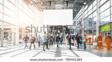 large crowd of anonymous blurred people at a trade show, including copy space banner 