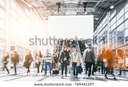 large crowd of anonymous blurred people at a trade fair, including copy space banner