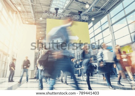 crowd of anonymous blurred people rushing at a trade show