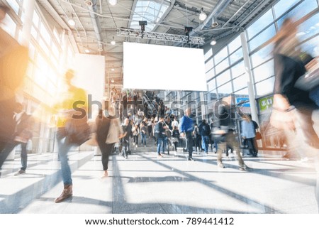 large crowd of anonymous blurred people walking at a trade show