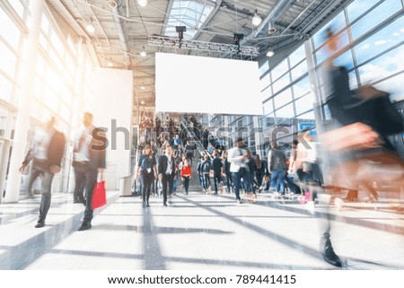 large crowd of anonymous blurred people in a modern hall