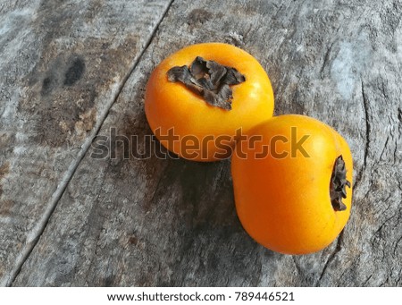 Close up picture of Persimmon on vintage wooden board. Orange color fruit for healthy eating. Delicious and sweet.