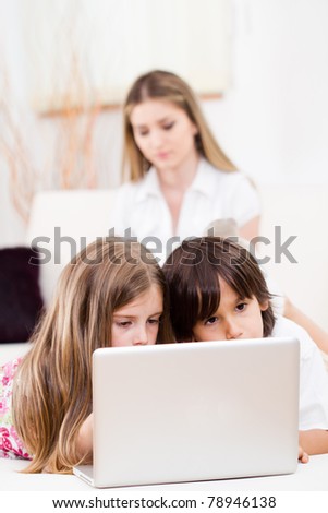 Brother and sister with laptop laying on the floor at home