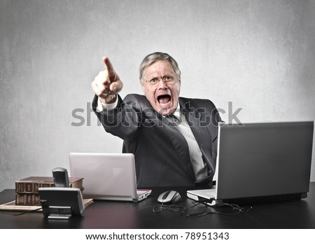 Angry senior businessman sitting at his desk and screaming Royalty-Free Stock Photo #78951343