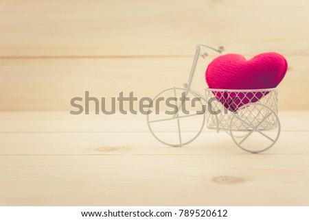 Valentine's day / everlasting love or special occasion concept : Small red pillow heart in a white bicycle on wood texture background with copy space, depicts strong love passion for romantic couple.