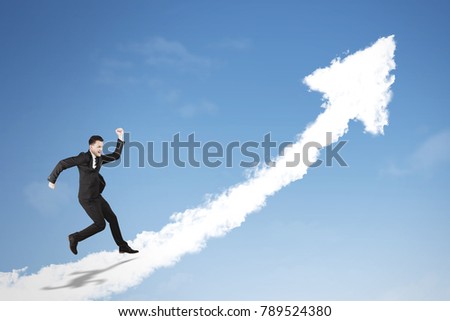 Picture of Caucasian businessman running on a cloud shaped upward arrow in the blue sky