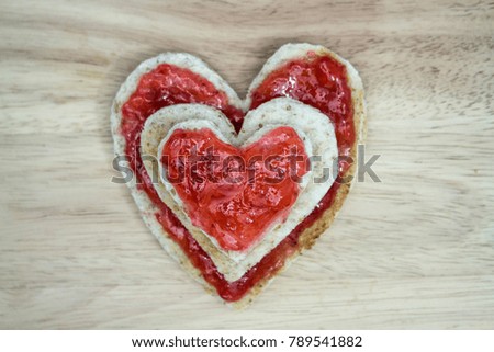 Bread heart sandwich and Heart shaped toast with fresh Strawberry jam on wooden background.
