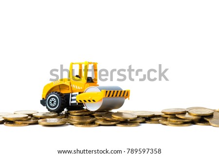 Mini Road roller machine with pile of gold coin, isolated on white background with copy space, business finance and banking industrial concept idea.