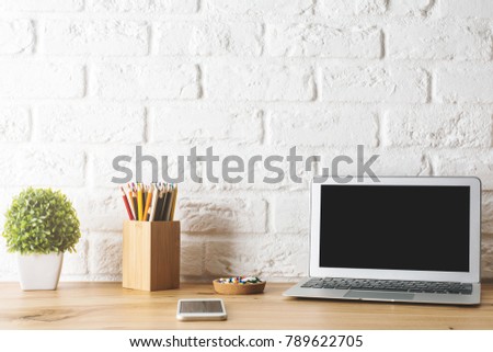Close up of creative designer desk with empty laptop, supplies and other items. Technology and device concept. Mock up 