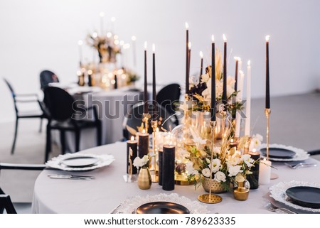 Black candles on candlesticks with flowers in vases on reception table. Wedding. Decor Royalty-Free Stock Photo #789623335