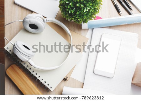 Top view and close up of creative wooden office desktop with empty cellphone supplies, headphones and other items. Leisure, hobby, break, work and occupation concept. Mock up