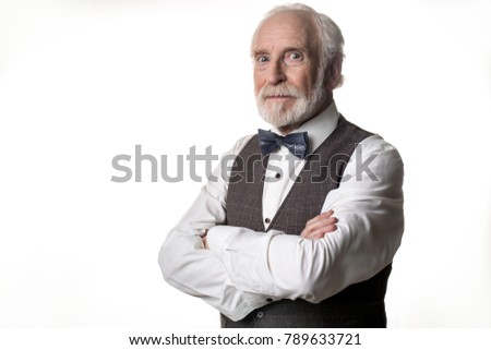 Portrait of calm old man looking at camera with suspicion and keeping his arms crossed on chest. Copy space in left side. Isolated on background